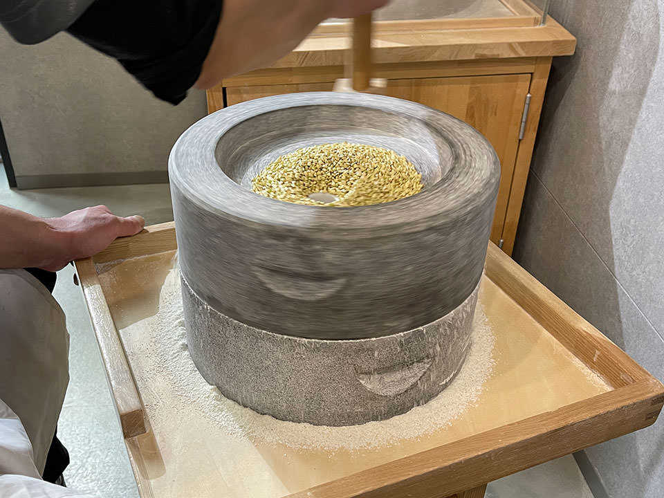 手挽きの石臼で製粉する高須さん